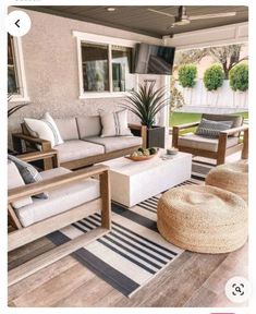 an outdoor living room with couches, chairs and rugs on the wooden floor