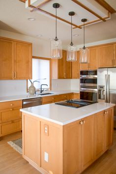 a kitchen with wooden cabinets and white counter tops, an island in front of the stove