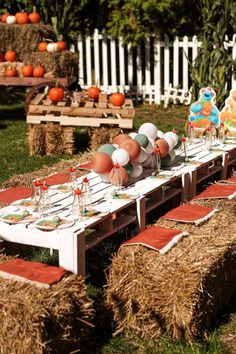 an outdoor table set up with hay bales and pumpkins