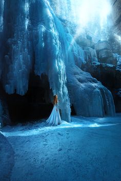 a woman is standing in front of an icy waterfall wearing a long white wedding dress