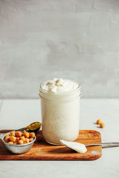 a jar of yogurt sitting on top of a cutting board next to spoons