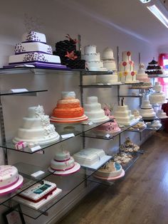 many different types of cakes on shelves in a room with wooden floors and hard wood flooring