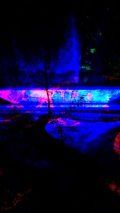 a skateboarder doing tricks in the dark with colored lights on it's side