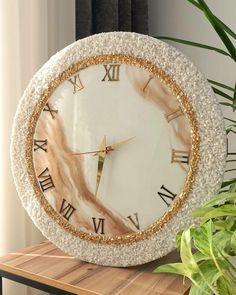 a clock that is sitting on top of a table next to a potted plant