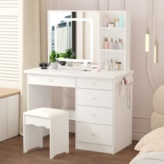 a white dressing table with mirror and stool in a room next to a window,