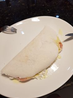 a piece of food on a white plate with a fork and knife next to it