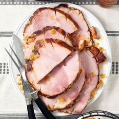 slices of ham on a plate with black handled utensils