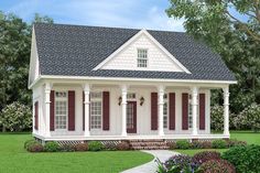 a small white house with red shutters on the front and side windows, surrounded by lush green grass