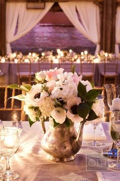 an elegant table setting with white flowers in a vase and wine glasses on the side