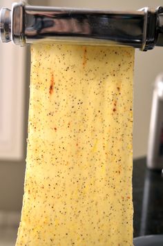 a piece of cheese is being held up by a metal roller on top of a counter