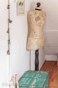 a mannequin sitting on top of a green box in front of a white wall