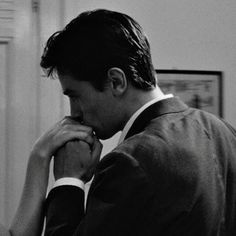 black and white photograph of a man in suit looking at his watch while he is holding his hand to his face