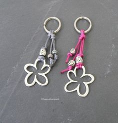 two silver and pink key chains with flowers on them