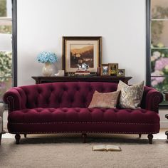 a living room filled with furniture and flowers on top of a carpeted floor next to windows