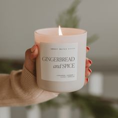 a woman holding a candle that reads gingerbread and spice