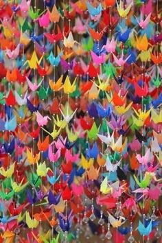 colorful origami birds are hanging from strings