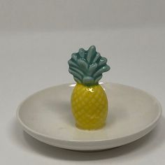 a small yellow pineapple sitting on top of a white plate