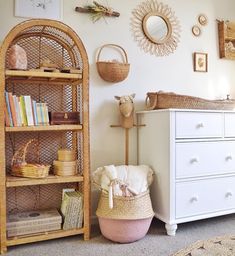 a white dresser sitting next to a baby crib in a room with pictures on the wall