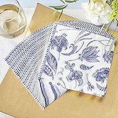 two napkins on top of a cutting board next to a vase with white flowers