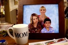 a coffee mug sitting on top of a table next to a photo frame with the word mom