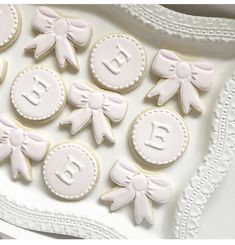 decorated cookies with bows and monograms are displayed on a platter for an elegant baby shower