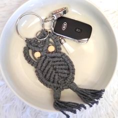 a crocheted owl keychain on a plate with a cell phone in it