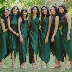 a group of women standing next to each other in green dresses