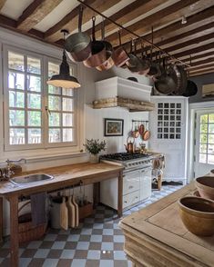 a kitchen filled with lots of pots and pans hanging from the ceiling next to a window