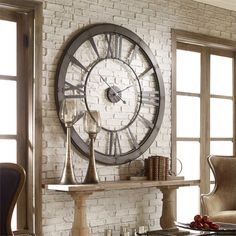 a large metal clock mounted to the side of a brick wall next to a table