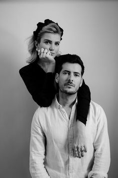 black and white photograph of a man holding a woman on his shoulders while they both look at the camera