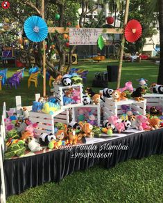 there are many stuffed animals on display in the grass at an outdoor event with umbrellas