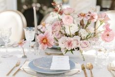 the table is set with silverware and pink flowers