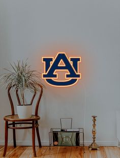 the auburn university logo is lit up on the wall above a table with a potted plant