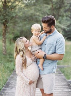 a man and woman holding a baby boy on a wooden walkway