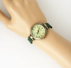 This is a round watch head, 1.25 inches diameter, made in alloy, aged bronze finished, free of nickel and lead. The wrist band is made in synthetic dark green suede. The clasp is magnetic and also made in alloy, aged bronze finish. The style is classy retro minimalist. Comes in a gift box. The strap comes in 9 different sizes: XS for a 6.00 inches wrist S for a 6.25 inches wrist M for a 6.50 inches wrist L for a 6.75 inches wrist XL for a 7.00 inches wrist XXL for a 7.25 inches wrist 3XL for a 7 Adjustable Green Analog Watch, Everyday Green Quartz Watch, Classy Watch, Retro Minimalist, Round Watch, Aged Bronze, Simple Leather, Casual Watches, Green Suede