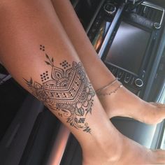 a woman's leg with a tattoo on it sitting next to a steering wheel