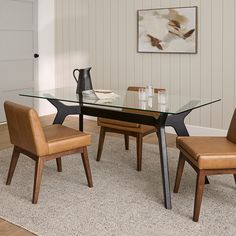 a glass dining table with two chairs and a vase on the end shelf in front of it