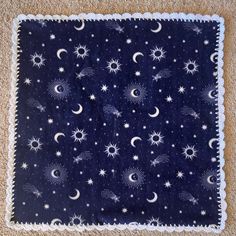 a blue and white blanket with stars and moon designs on it, sitting on the floor