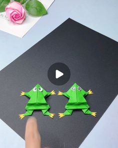 someone is making origami frogs out of paper and glues them to look like they are dancing