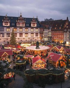 an outdoor christmas market with lots of lights and decorations on display in front of buildings