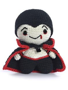 a crocheted doll with a black cape and red scarf on it's head