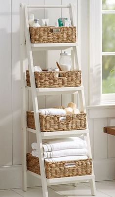 a white ladder shelf with baskets and towels on it