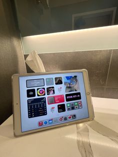 a tablet sitting on top of a white counter next to a toilet paper dispenser