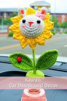 a crocheted sunflower sitting on top of a car dashboard with the words kawaii car dashboard decor above it