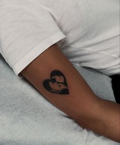 a person with a heart shaped tattoo on their arm