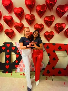 two women standing next to each other in front of hearts