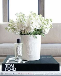 white flowers are in a vase on top of books