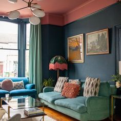 a living room with blue couches and green curtains on the window sill,