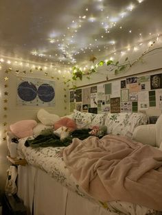 an unmade bed in a dorm room with lights on the ceiling and pictures above it