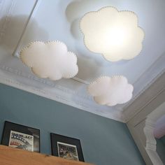 three white clouds are hanging from the ceiling above a shelf in a room with blue walls